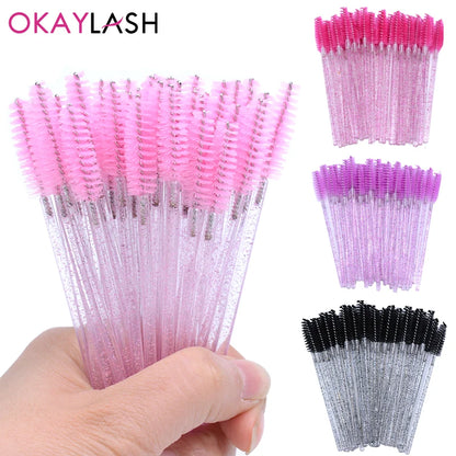 OKAYLASH glitter eyelash mascara wands with crystal handles in various colors, designed for precise and hygienic lash application. Includes 50 disposable spoolie brushes.