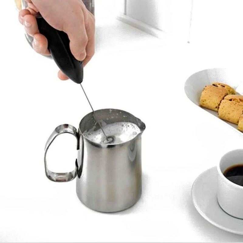 Handheld electric milk frother with stainless steel spring, black and silver. Battery-powered for efficient mixing of milk, coffee, and eggs.