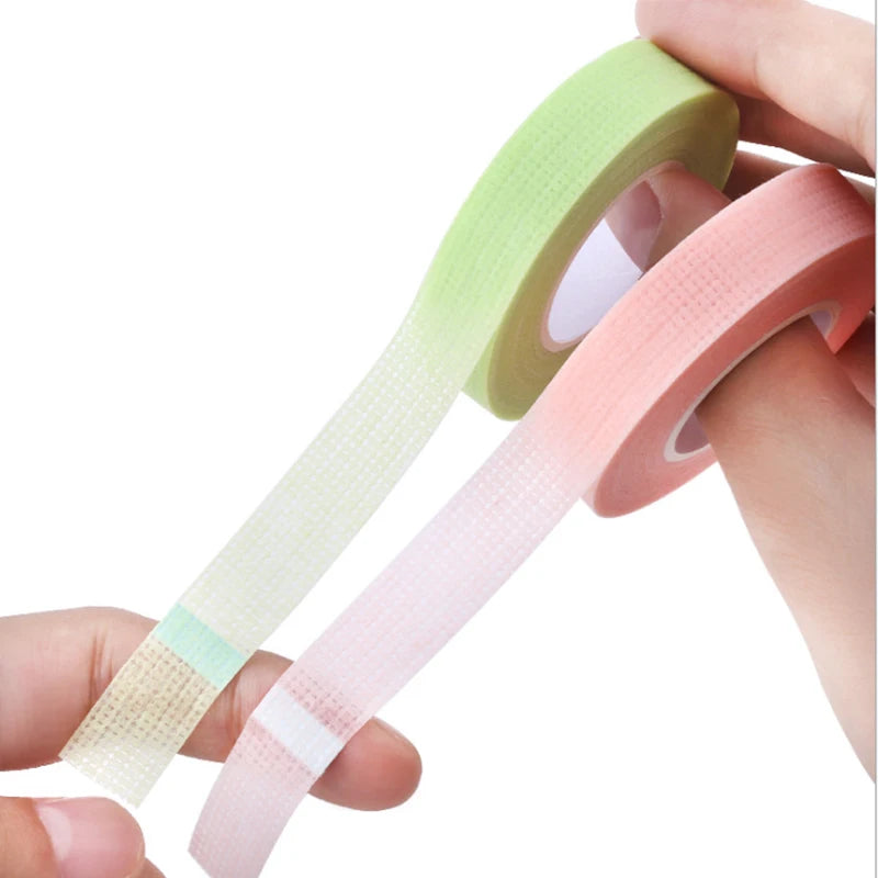 Multiple rolls of colorful micropore eyelash tape for lash extension and lifting, featuring pink, green, white, blue, and purple colors.